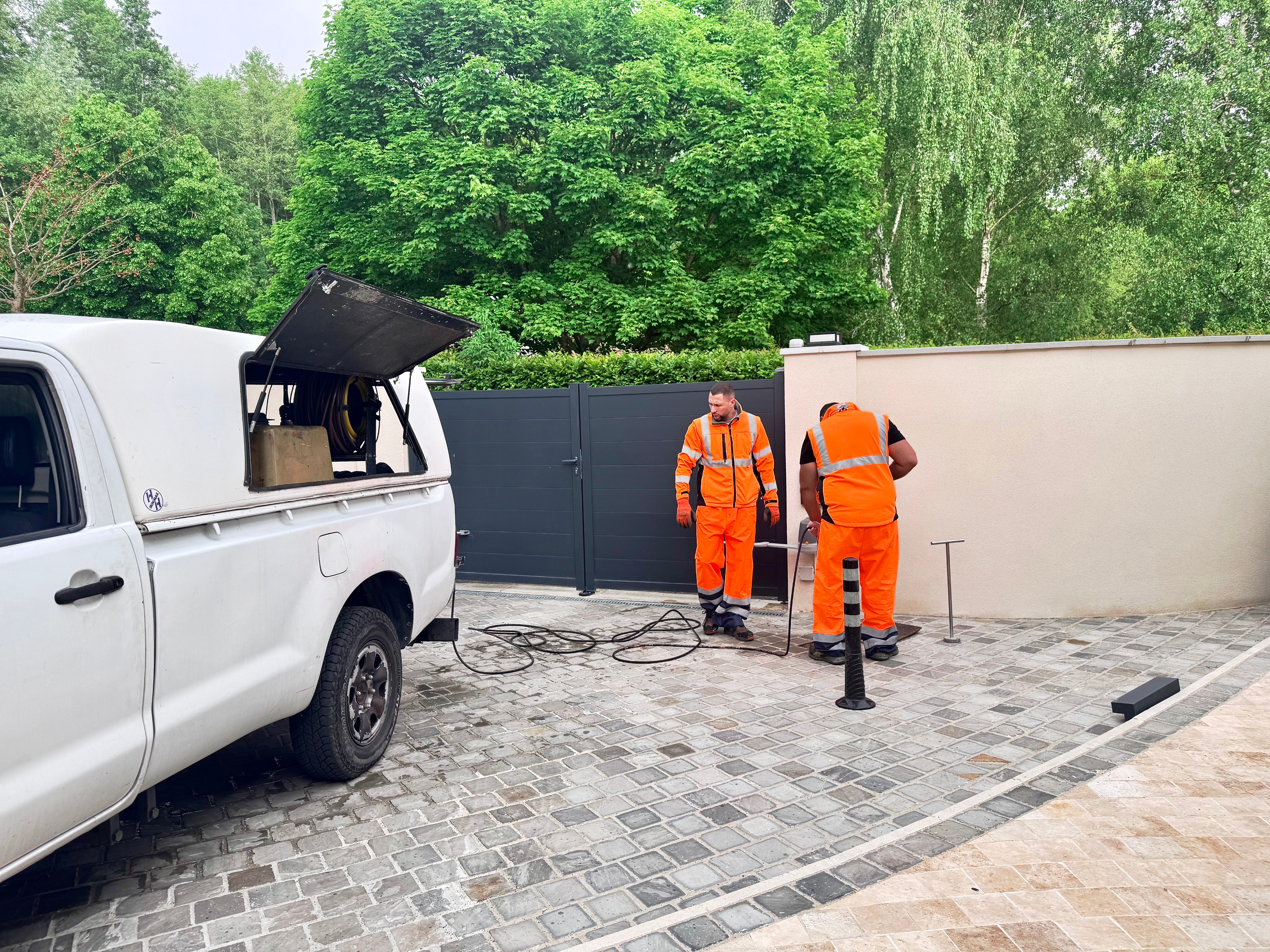 Photo de deux techniciens en train d'exécuter un travail de débouchage de canalisation. 