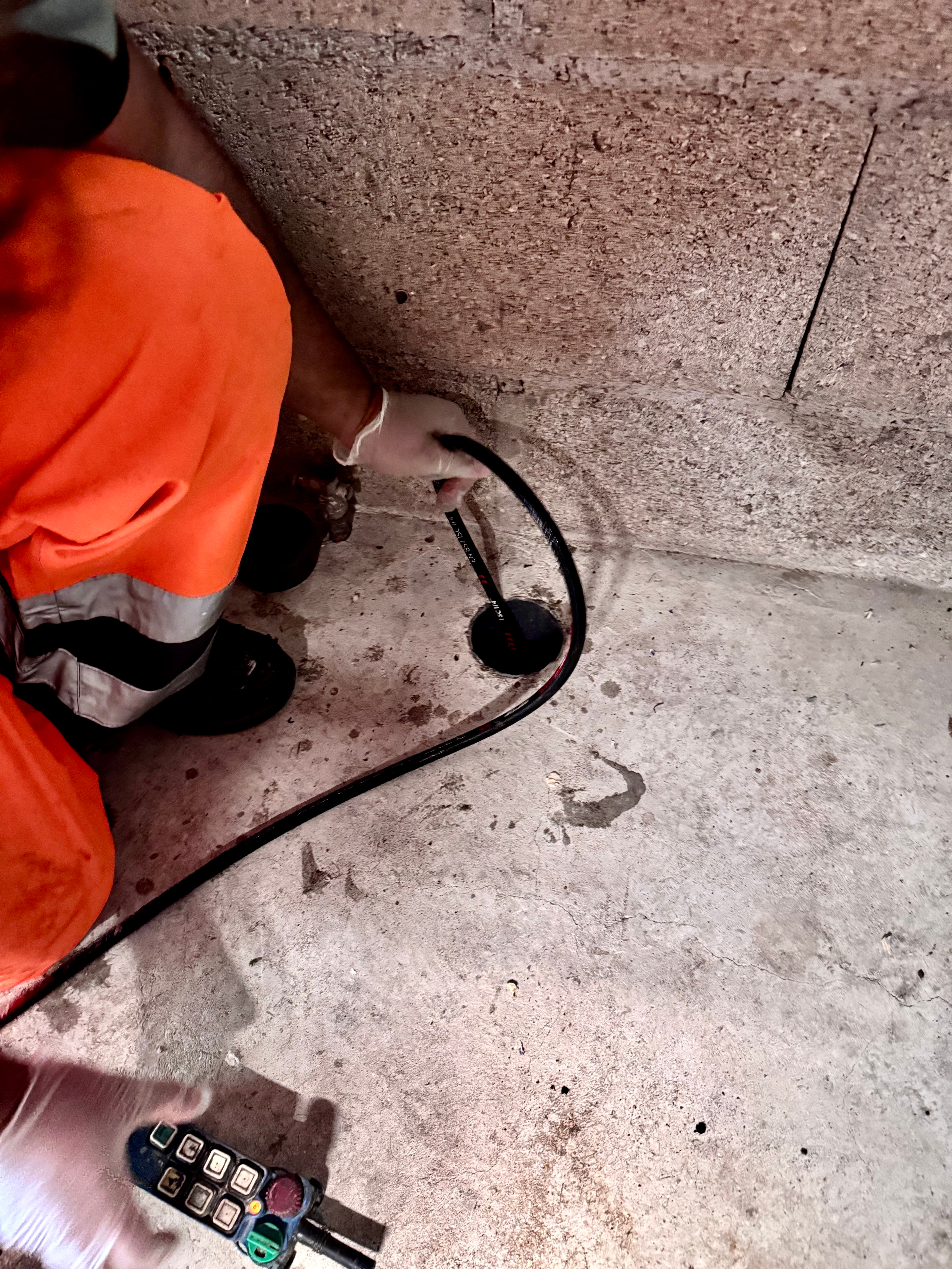 Photo d'un technicien en pleine action avec un tuyau afin de déboucher le regard. 
